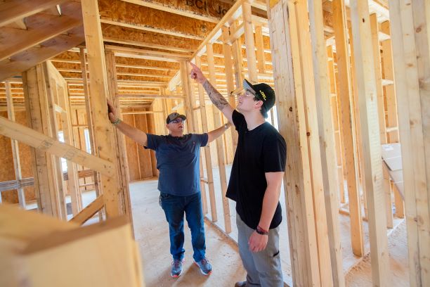  Instructor Ron Meinert reviewing building techniques with recent graduate Shane Bhatti at a home under construction at Spring Village Estates. 