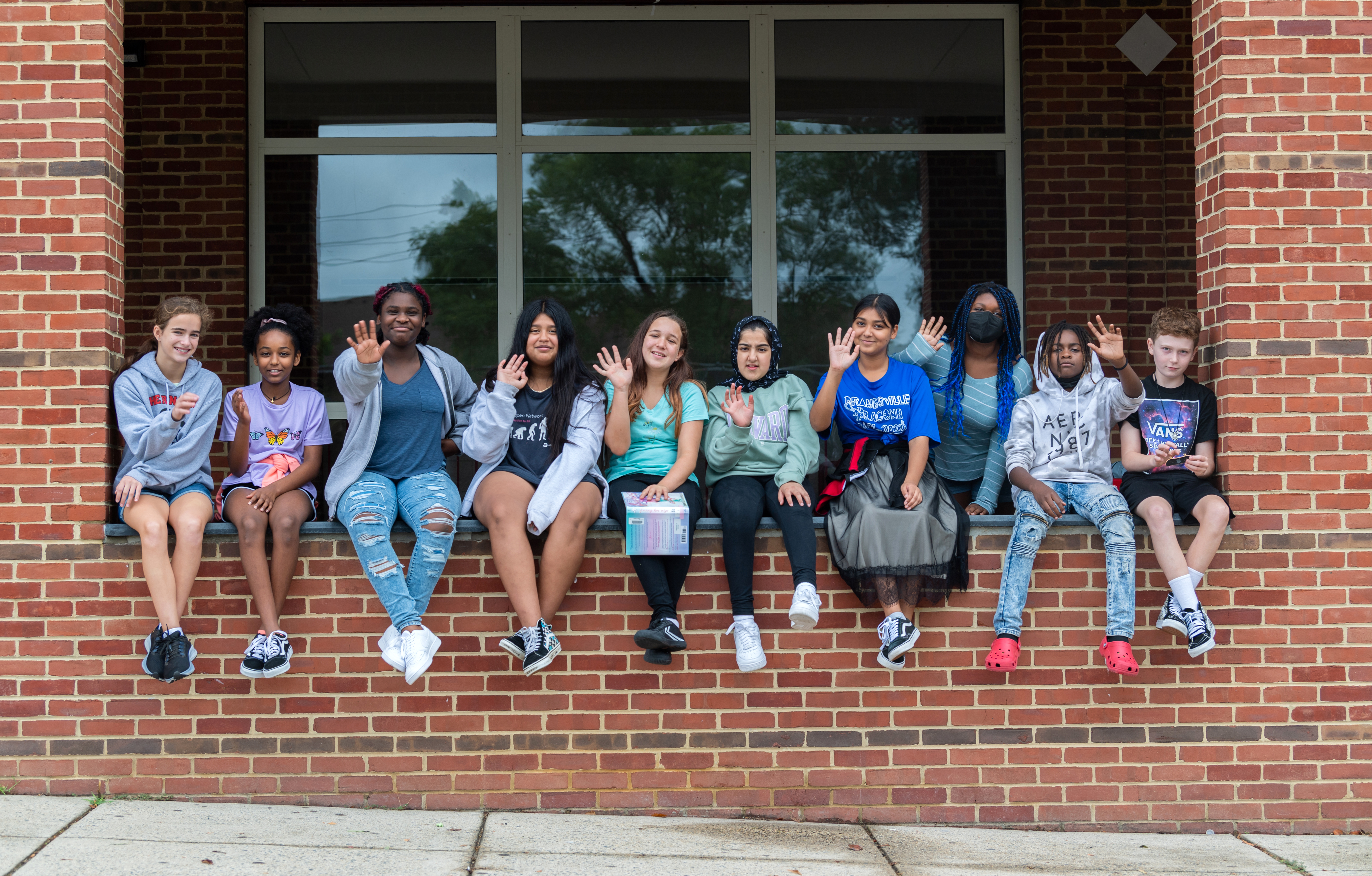 A group of female students from Herndon Middle School sit on a wall.