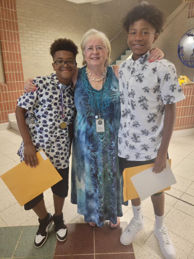Substitute Bunni Cooper, 76, stands in between two of the students she has worked with at Bull Run ES.