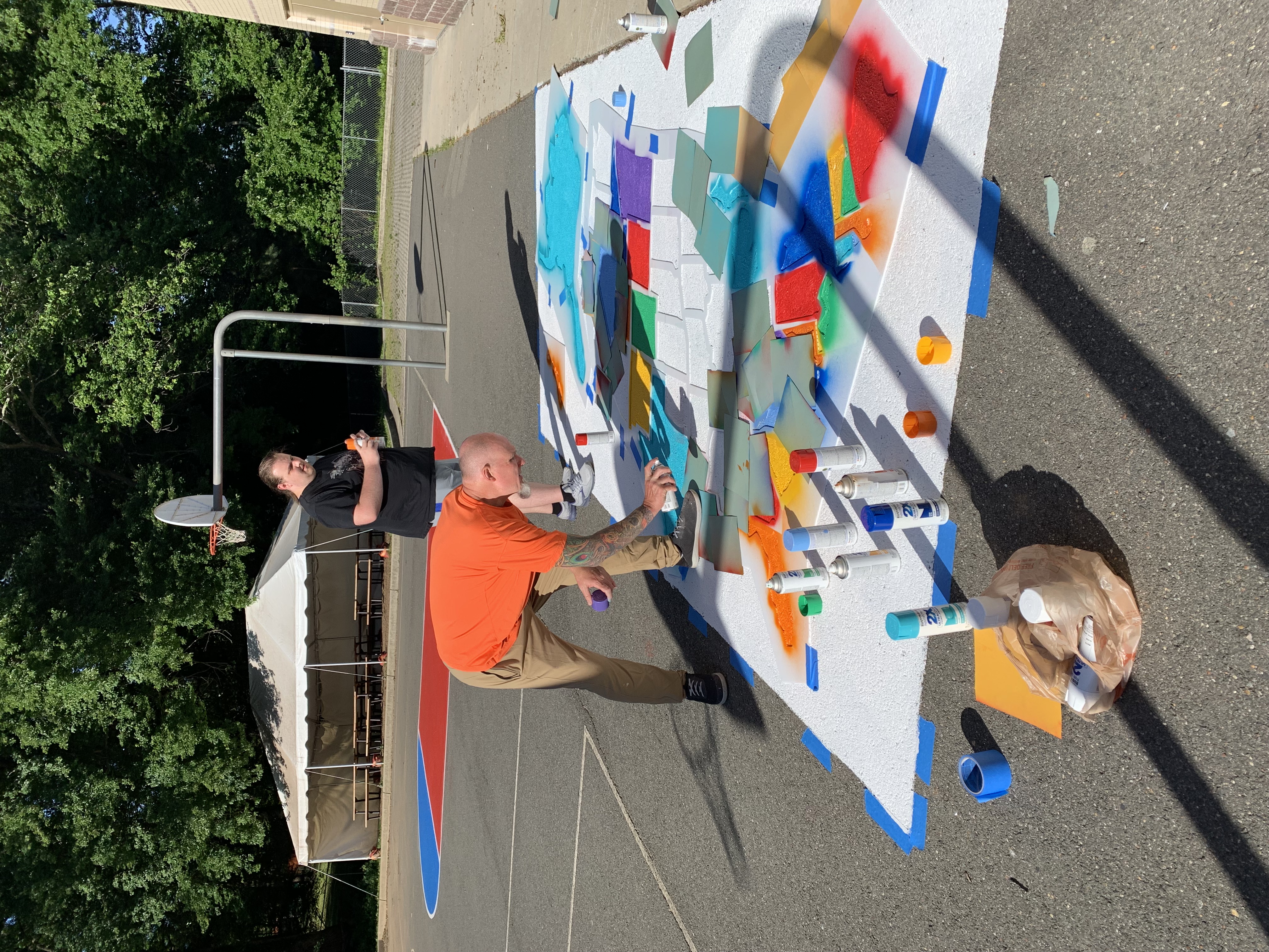 Staff paints a design on the blacktop. 