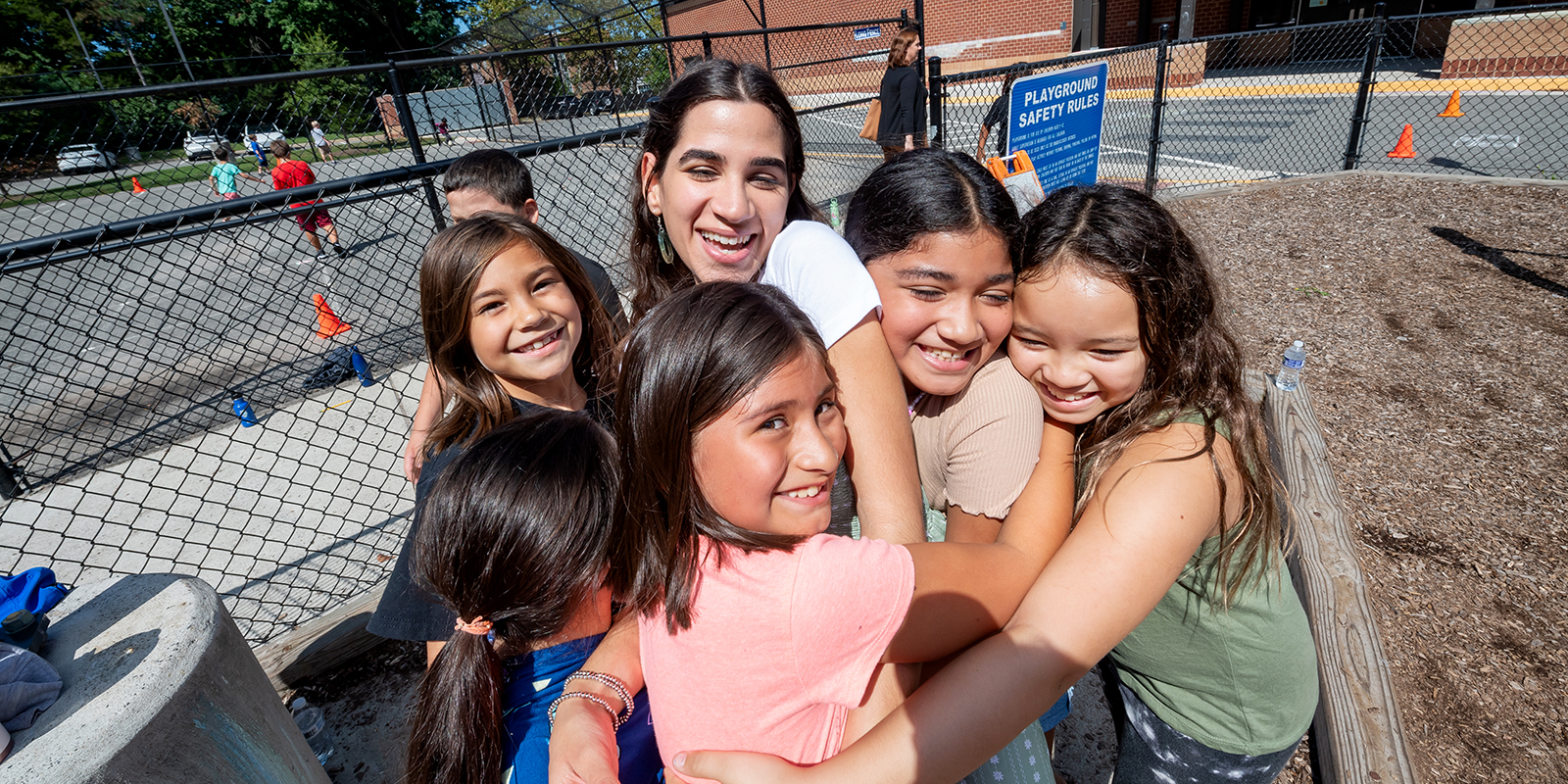 Third-grade Spanish immersion teacher Gabriela Muriente is hugged by her students on the playground.