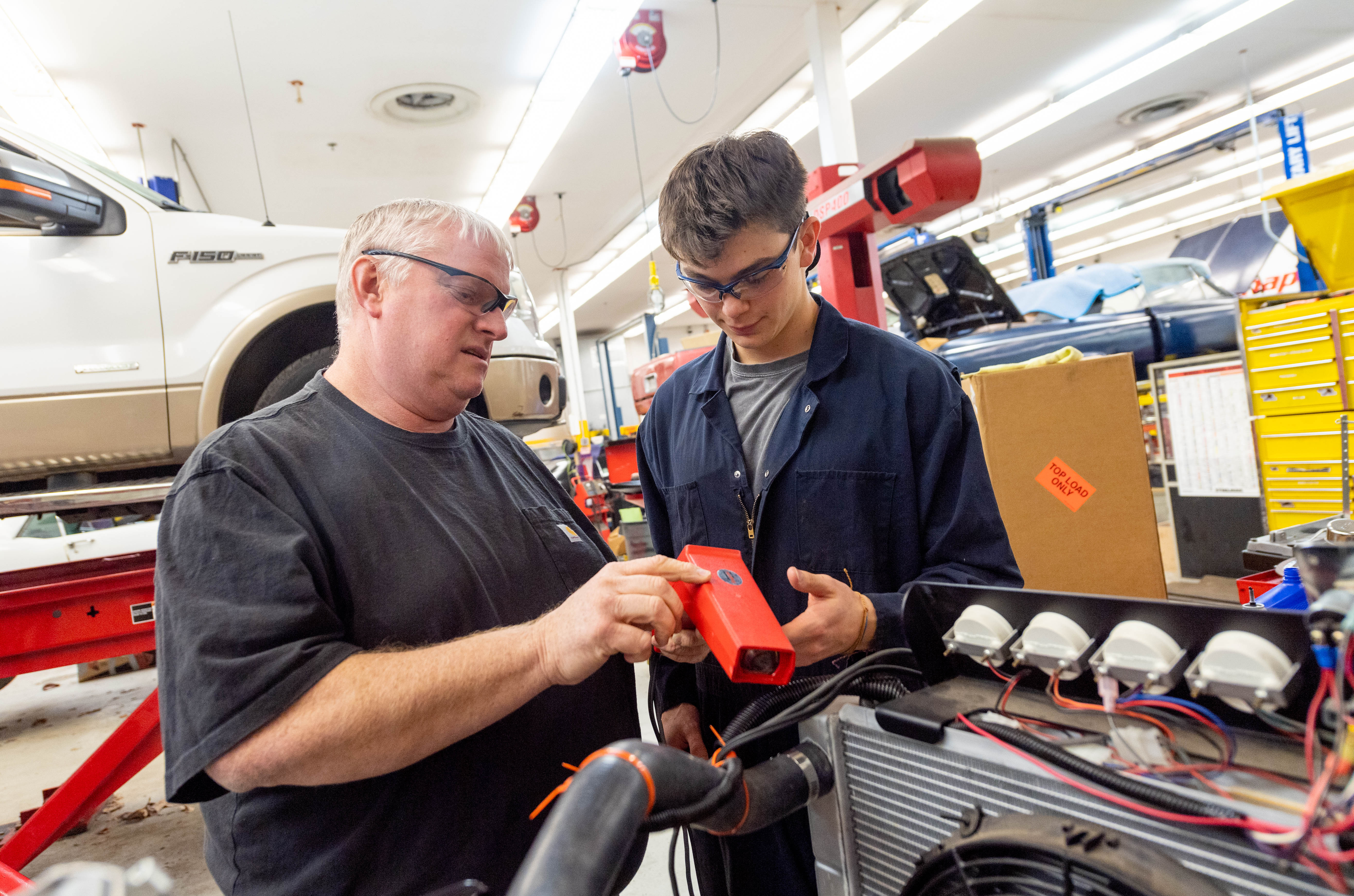 Lake Braddock automotive tech teacher David Plum works with a student in the auto shop classroom.