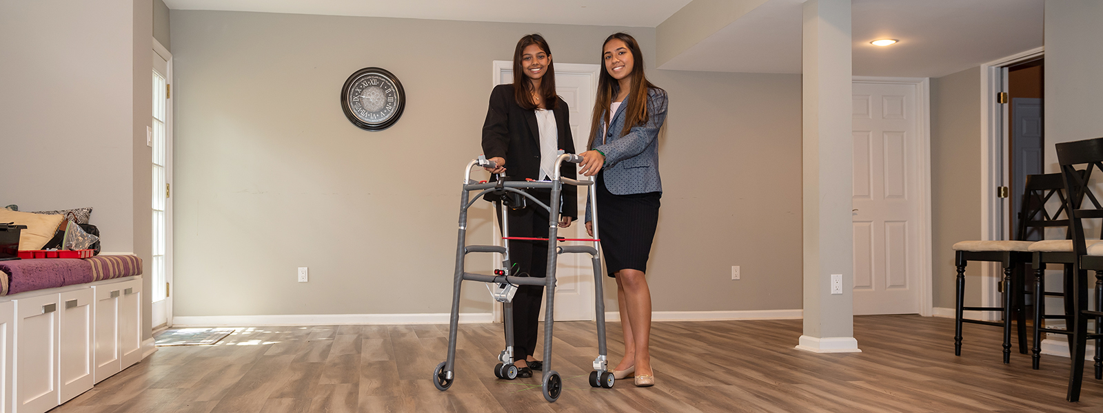 Kaavya Karthikeyan and Akanksha Tibrewala stand in front of AutoTrem, an automatic walker they designed to assist people with mobility issues.