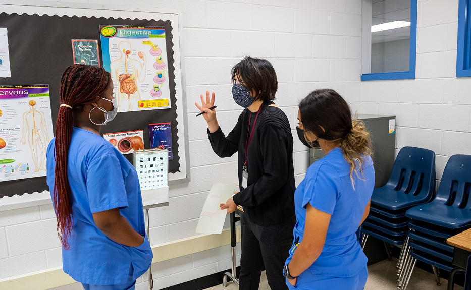 A nurse reviews how to do an eye exam with Falls Church Academy Medical Assistant students. 