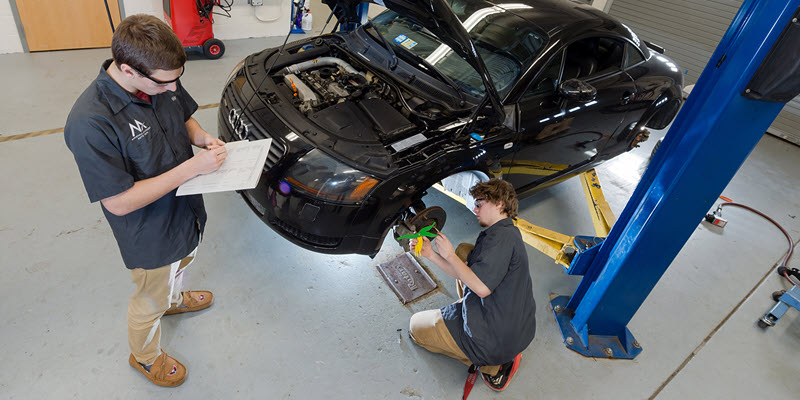 two students working to fix a car