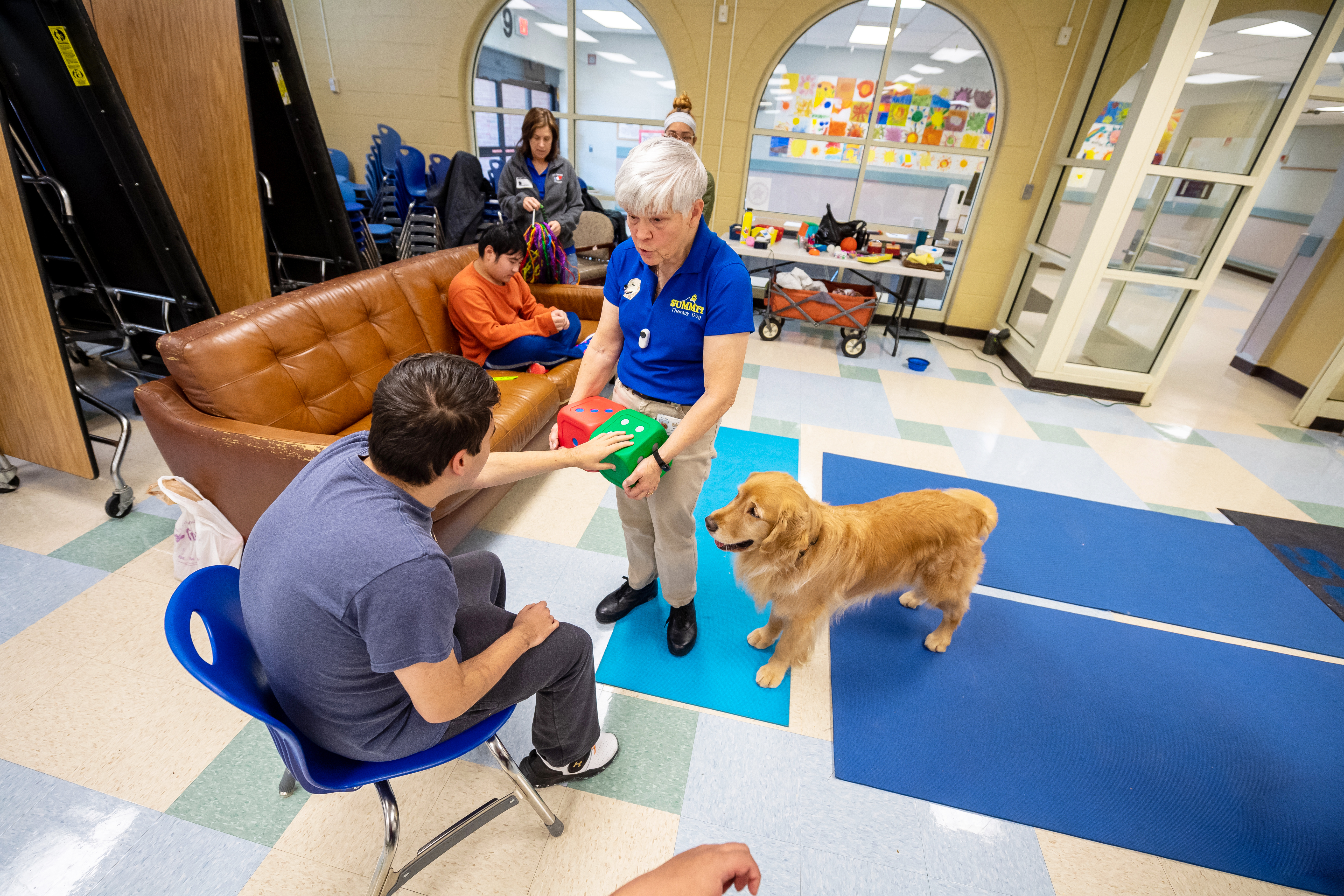 A student plays a dice game with Micah the therapy dog. 