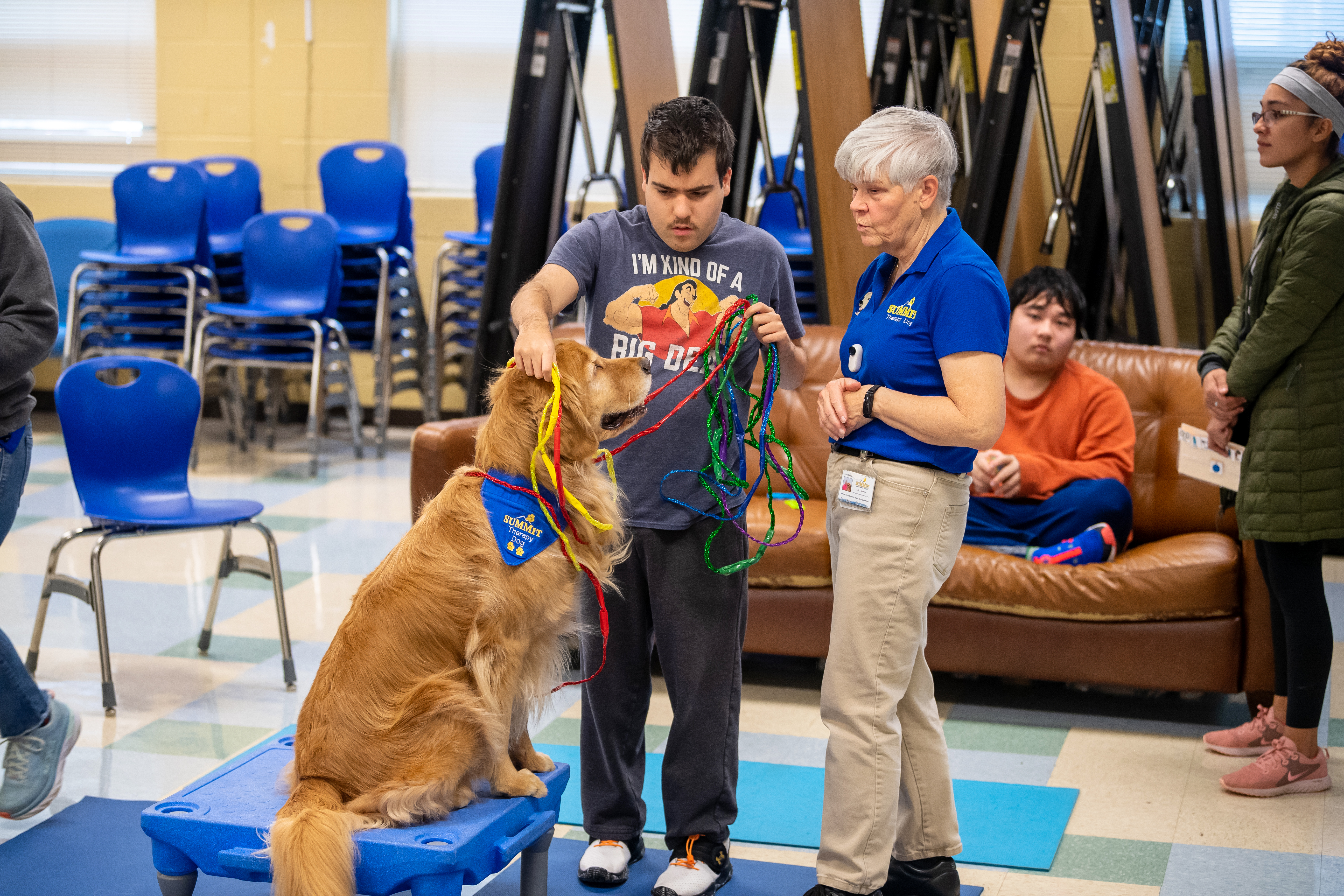 A student puts 'necklaces' on Micah the therapy dog. 