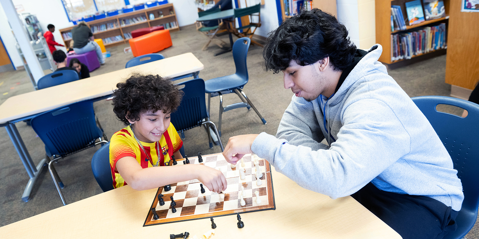 two students playing chess together