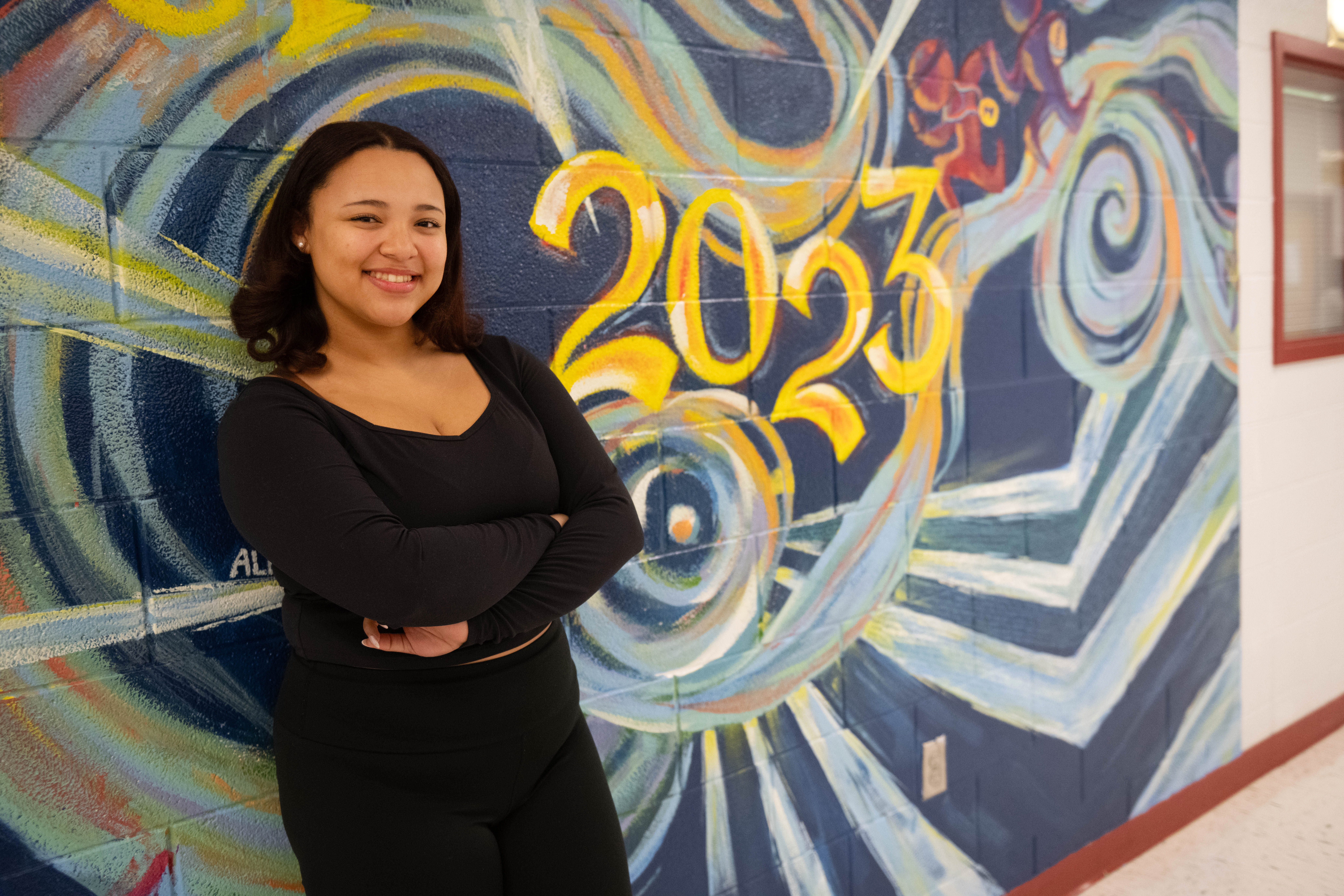 Mackenzie standing in front of a class of 2023 mural.
