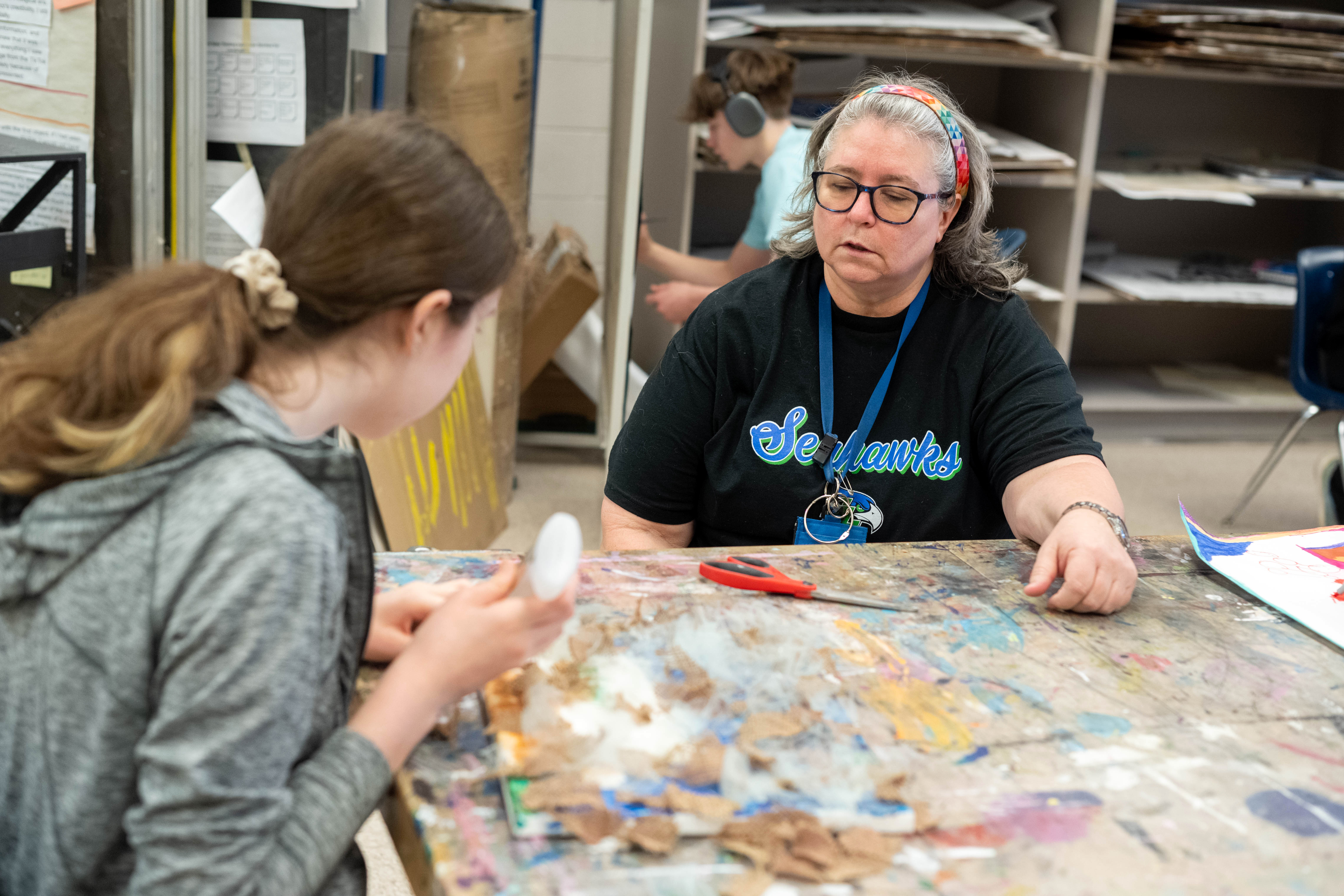 Co-teacher Claudia Harvey helps a student with her project - a series of fabrics glued onto canvas.