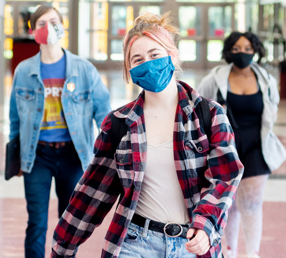 students in masks walking in school hallways