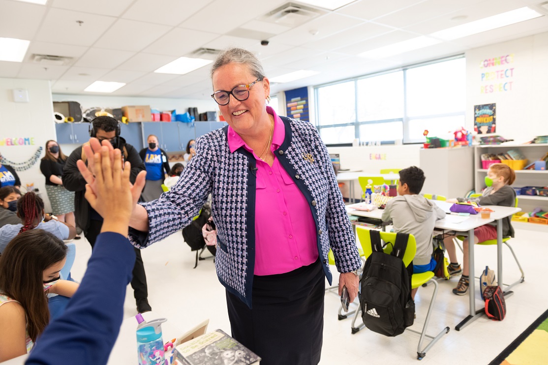 Dr. Reid high-fives a student during a school visit. 