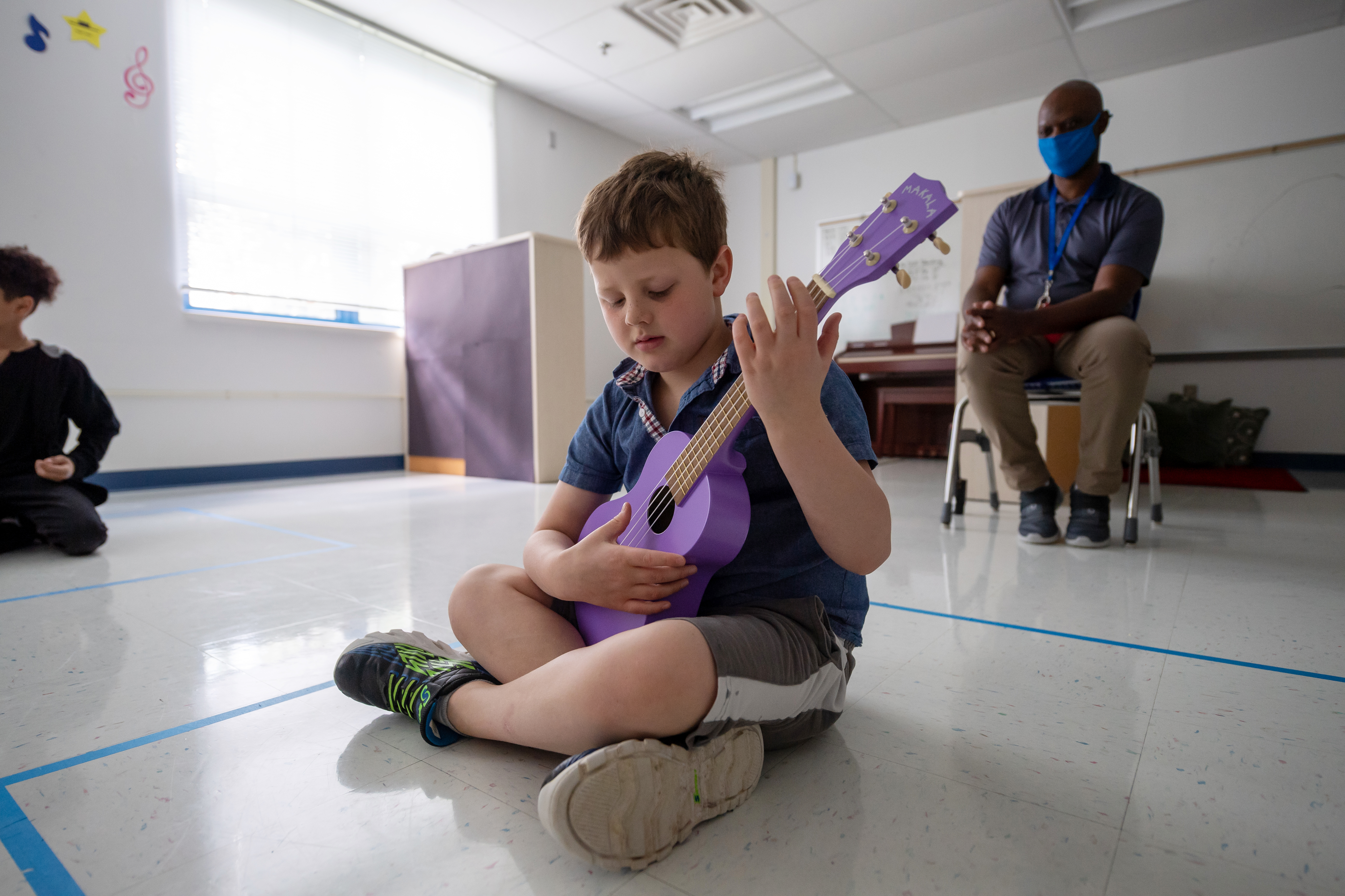 A student practices his song on the ukulele. 