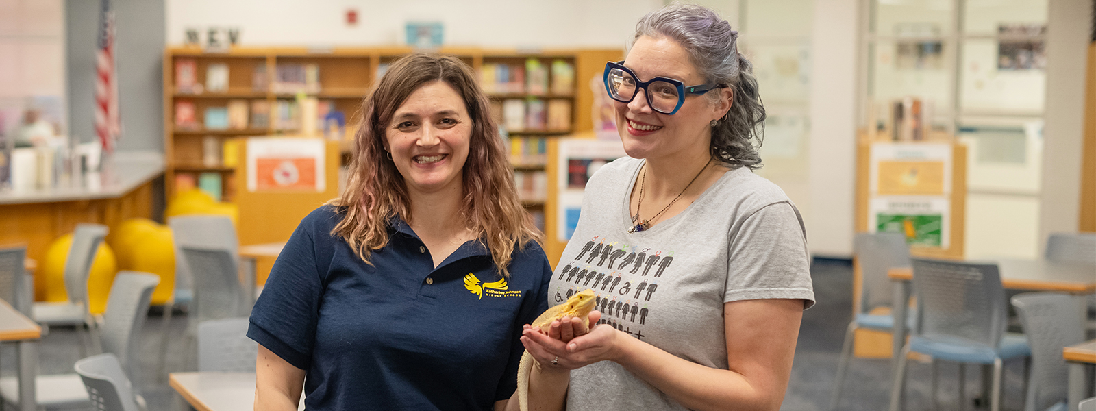 Two librarians hold a bearded dragon. 