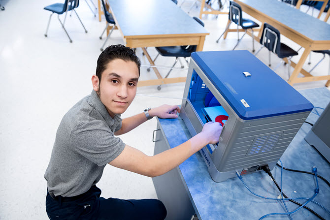 a teenage boy using a 3D printer