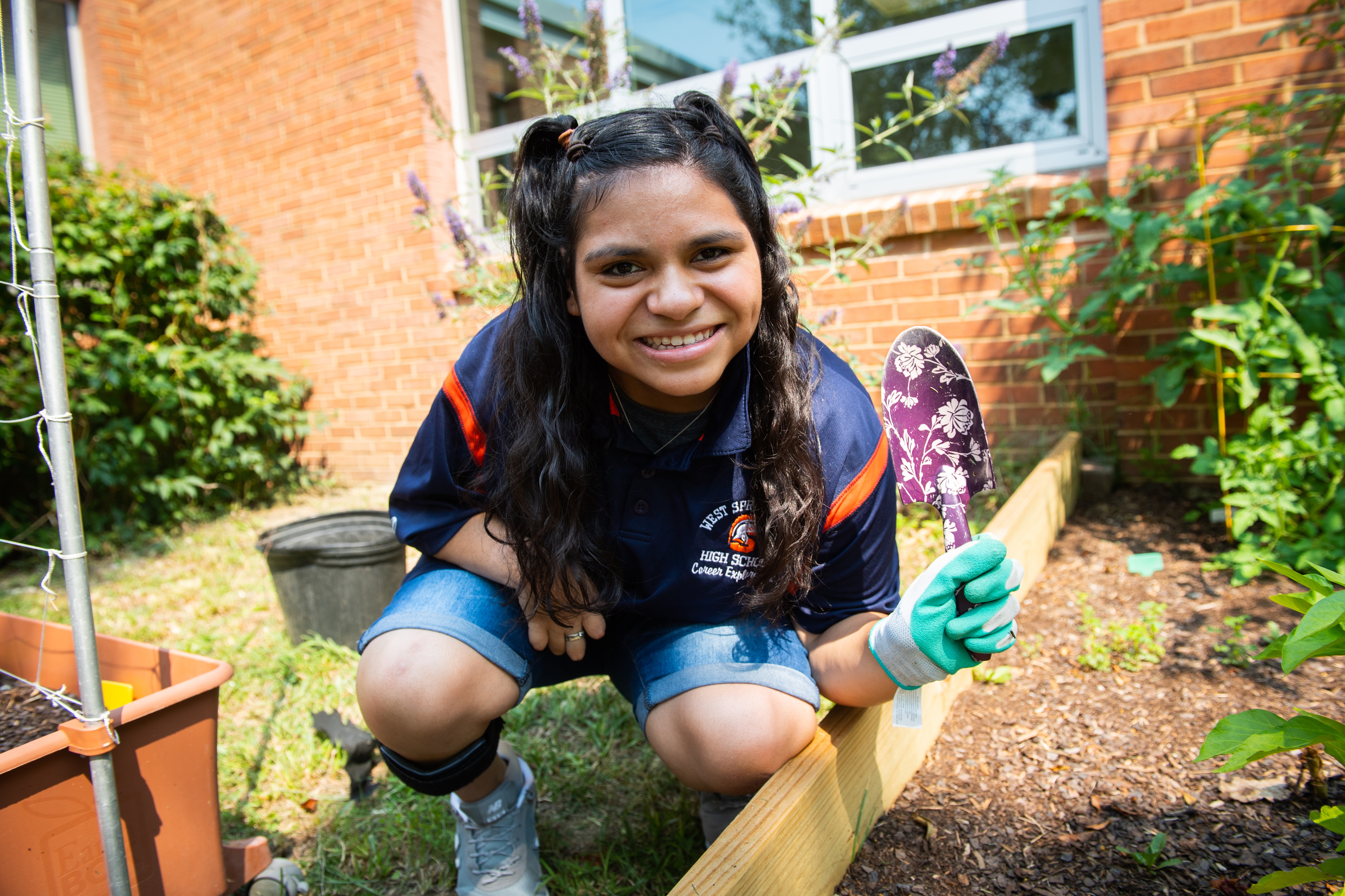 A female student tends to a flower bed.