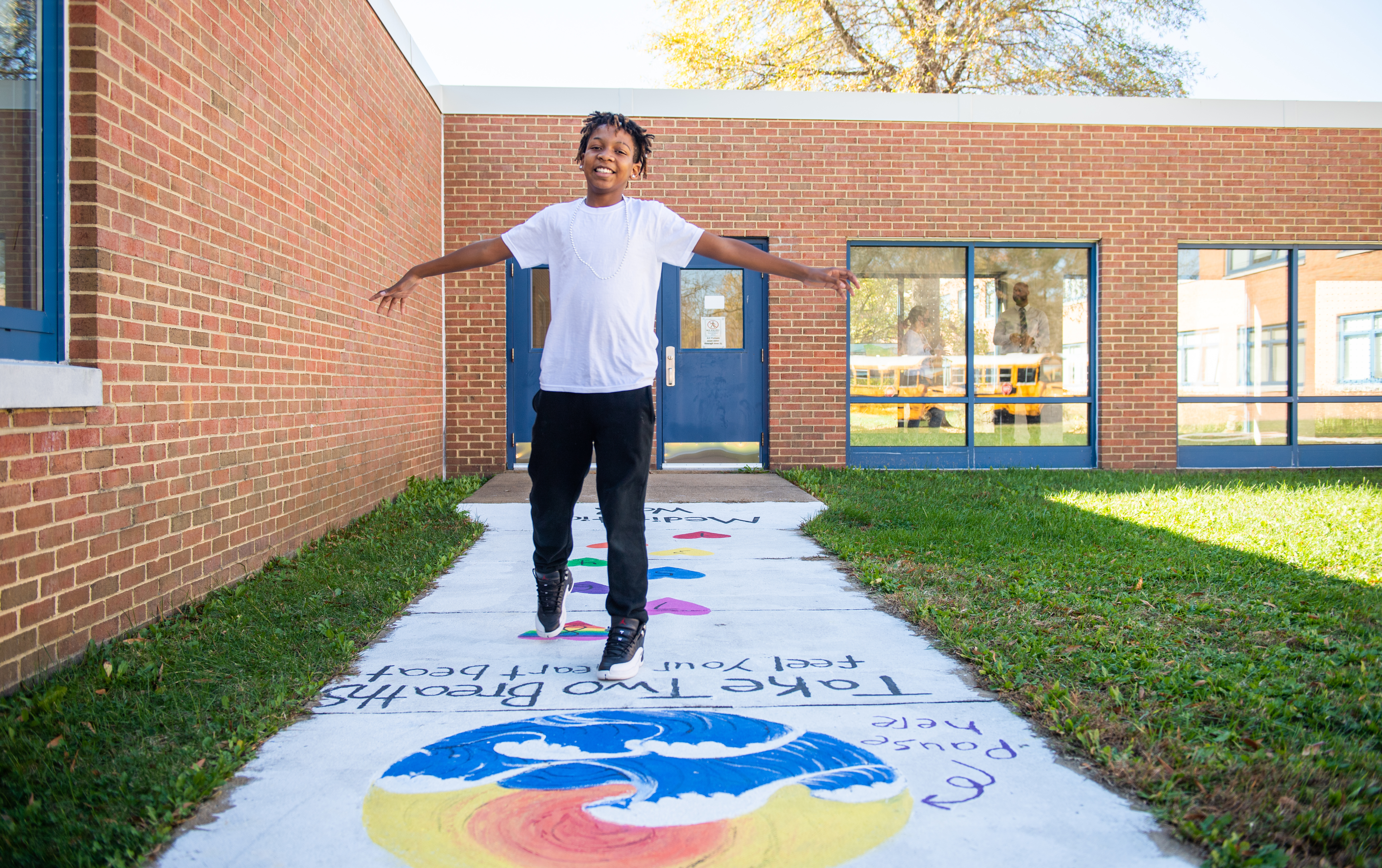 A student from Walt Whitman Middle School plays on a chalked path