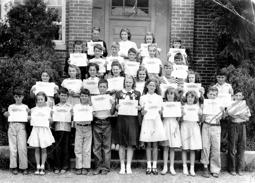 Black and white photograph of a group of students posed on the steps of Annandale Elementary School. They are holding certificates.