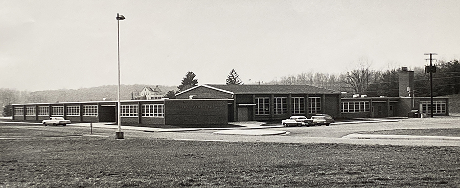 Black and white photograph of Chapel Square Elementary School taken from a hill overlooking the school. The front and one side of the building are visible.