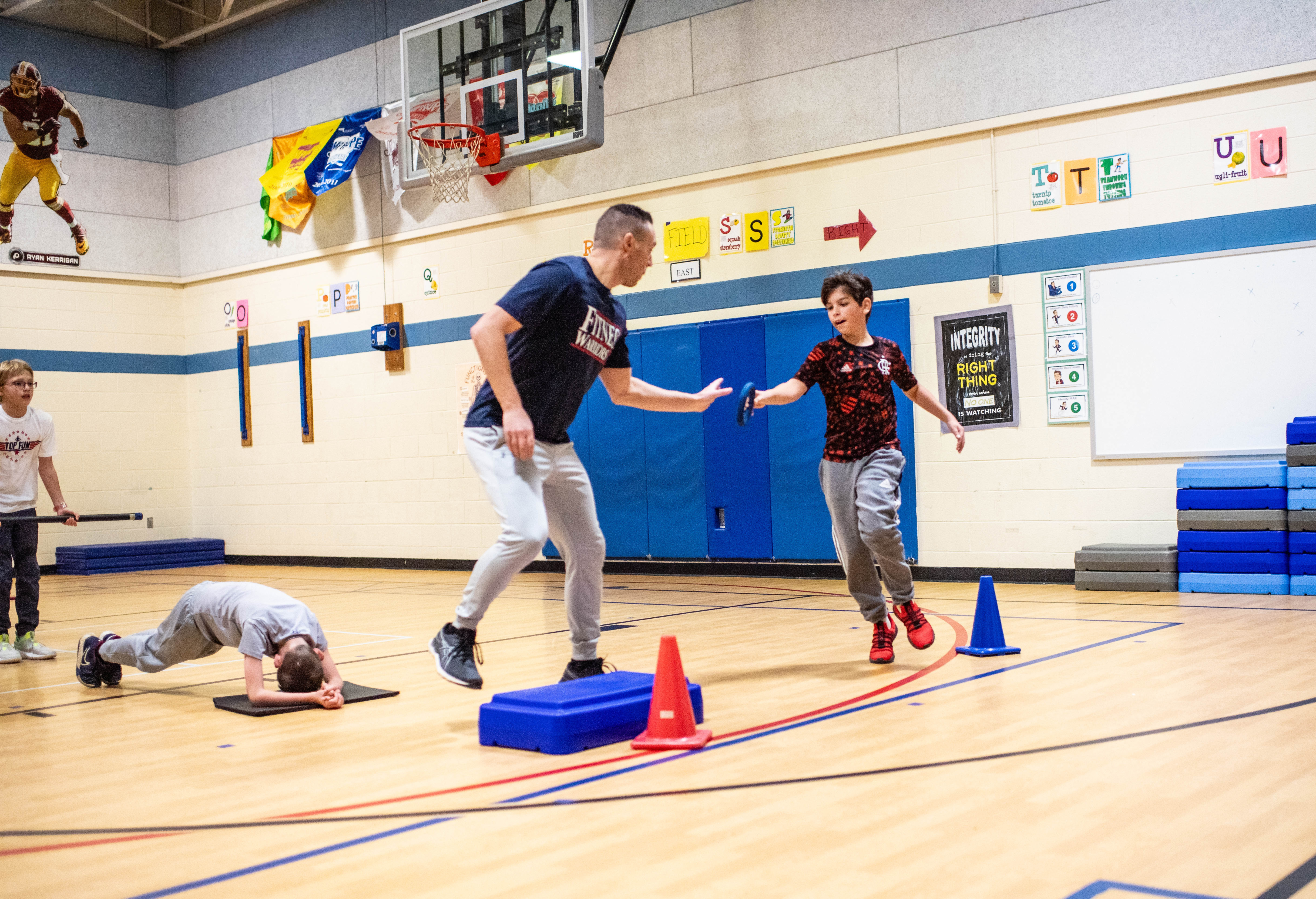 Chesterbrook's physical education teacher Jay Levesque hands off a ring to a student during a workout.