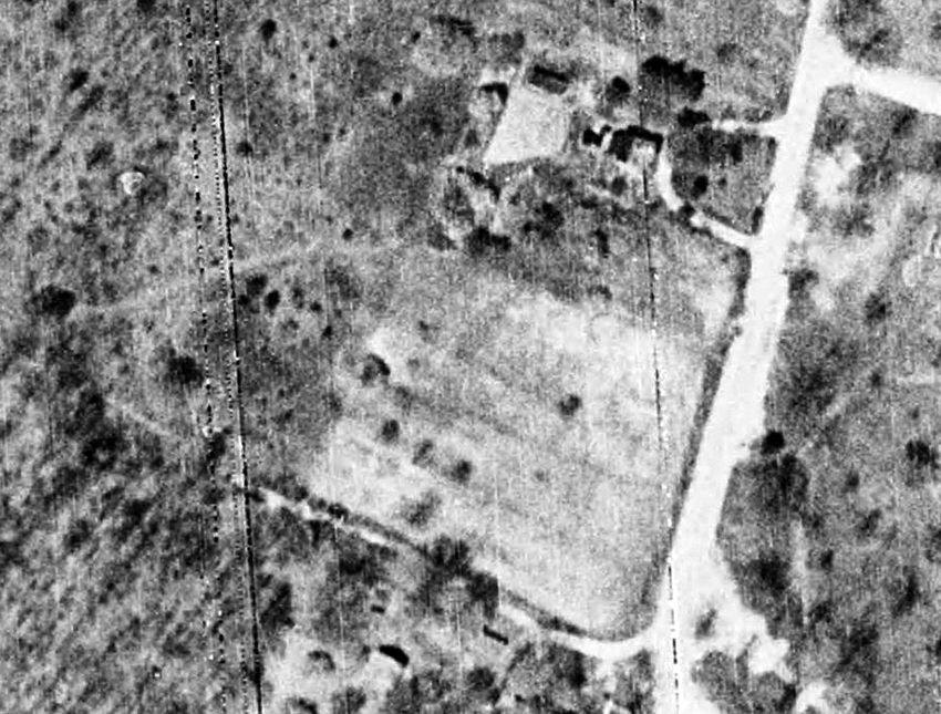 Aerial photograph of the Dunn Loring Elementary School site. The landscape is mostly wooded with a farm field at the corner of Gallows Road and Idylwood Road. A small farmhouse is north of the field.