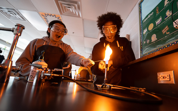 Students work with Bunson burners in a chemistry class