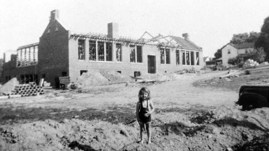 Photograph of Dunn Loring Elementary School during construction. A young girl stands in front of the building.