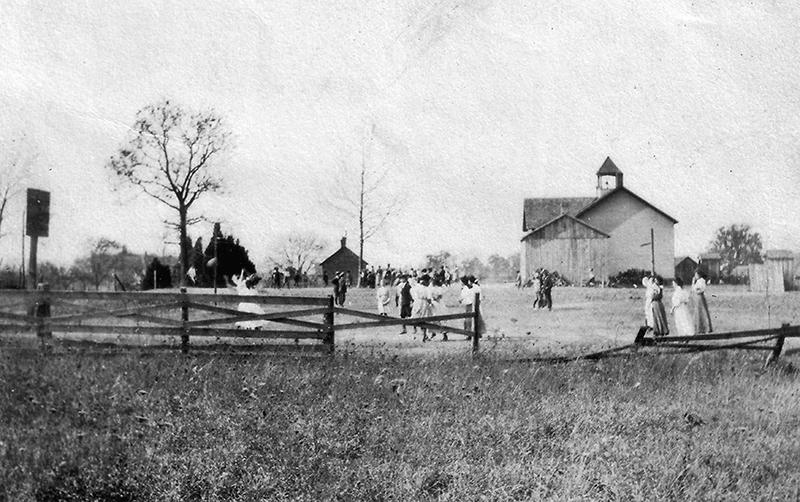 Black and white photograph of the three-room Floris School with students playing in the schoolyard.