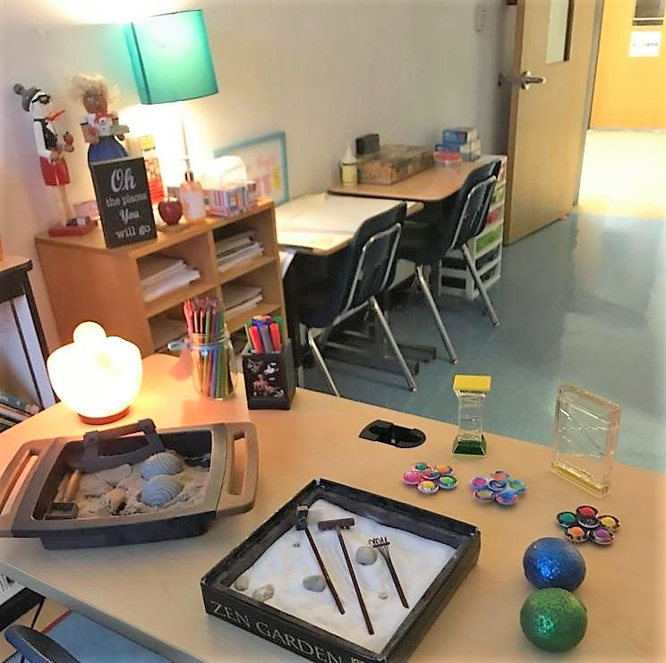 Calm resource room with soft lighting, coloring activities, sensory gadgets, kinetic sand, and soft music.