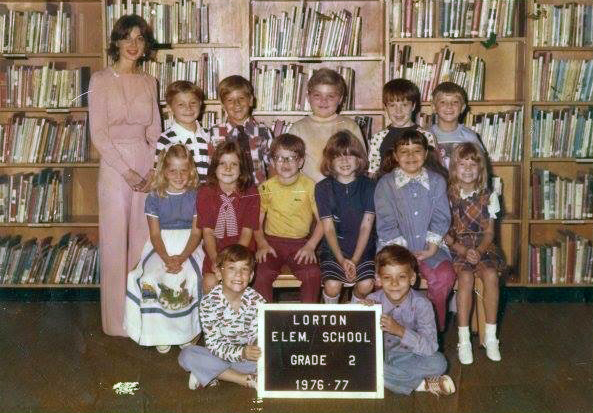 A class photograph from Lorton Elementary School. A group of 13 students and their teacher are posed in the library.