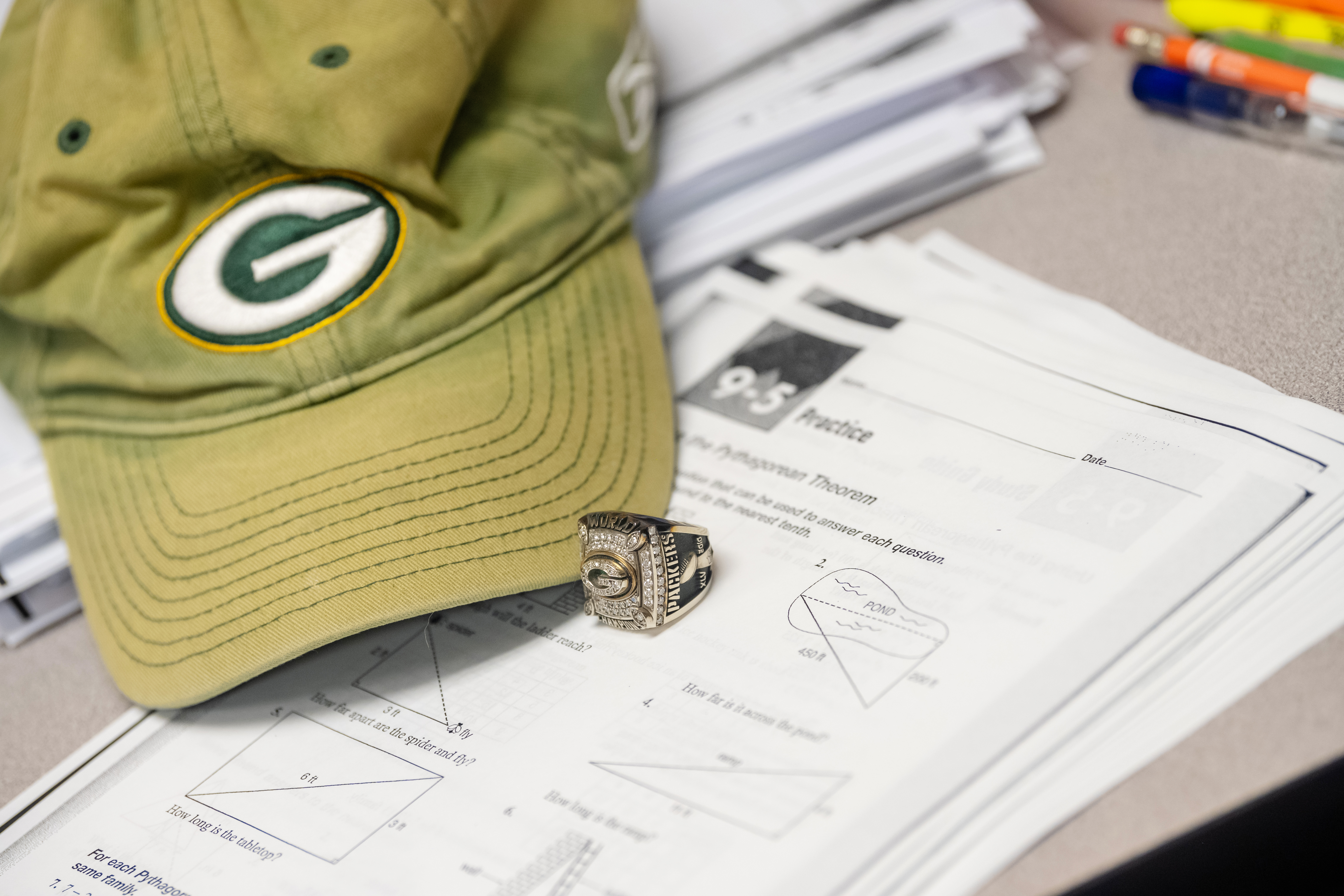 Malc's Packers hat and Super Bowl XLV ring lay on his desk, on top of geometry worksheets.