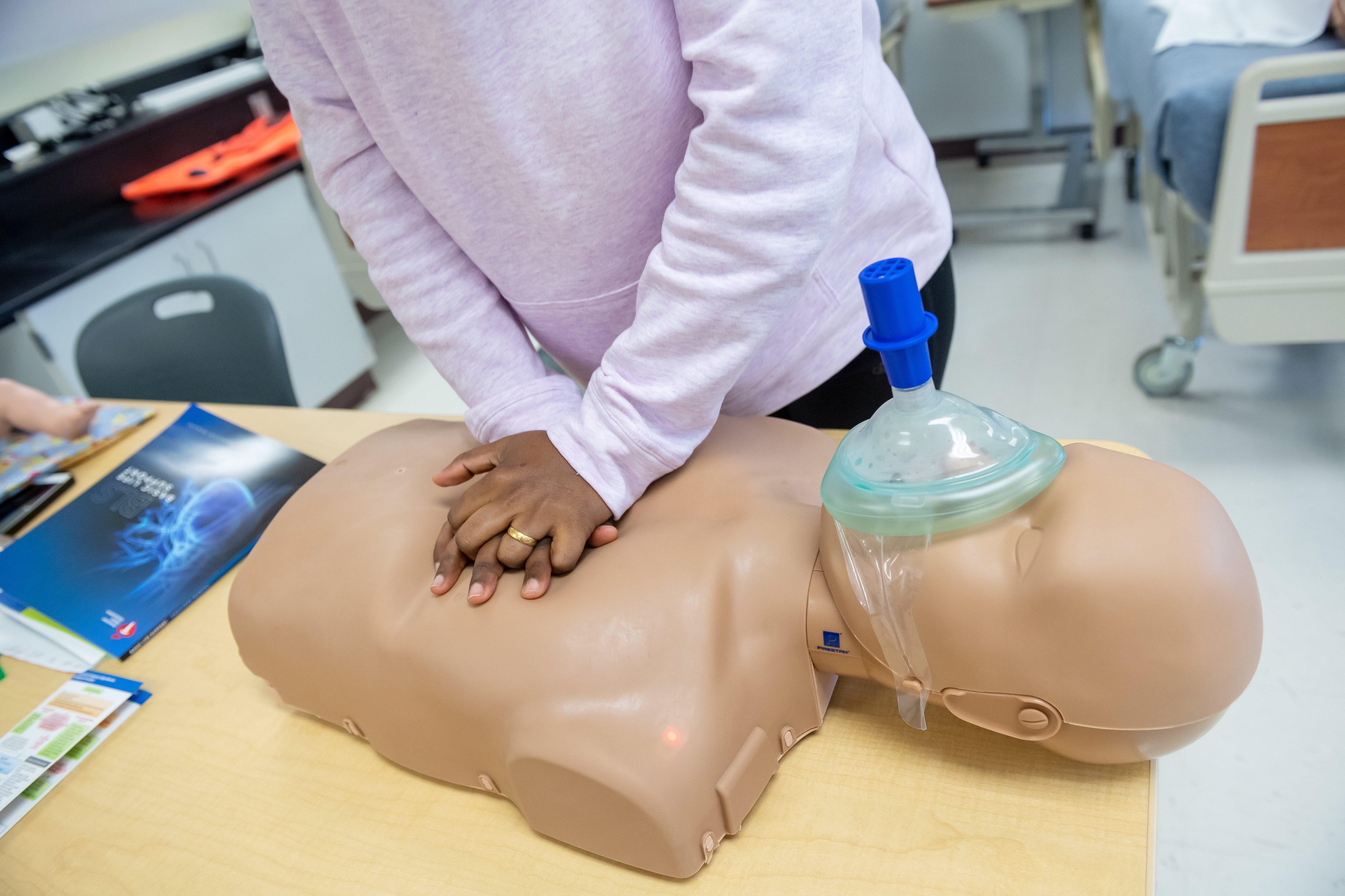 An FCPS instructor demonstrates how to conduct CPR on a mannequin.