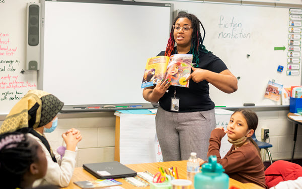 teacher reading book in front of classroom