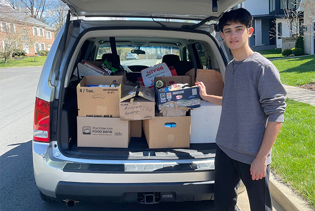 student standing by a car filled with donated food