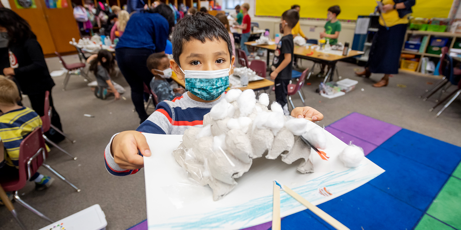 A Kindergarten student builds an igloo from an egg crate and cotton balls during Innovation Hour.