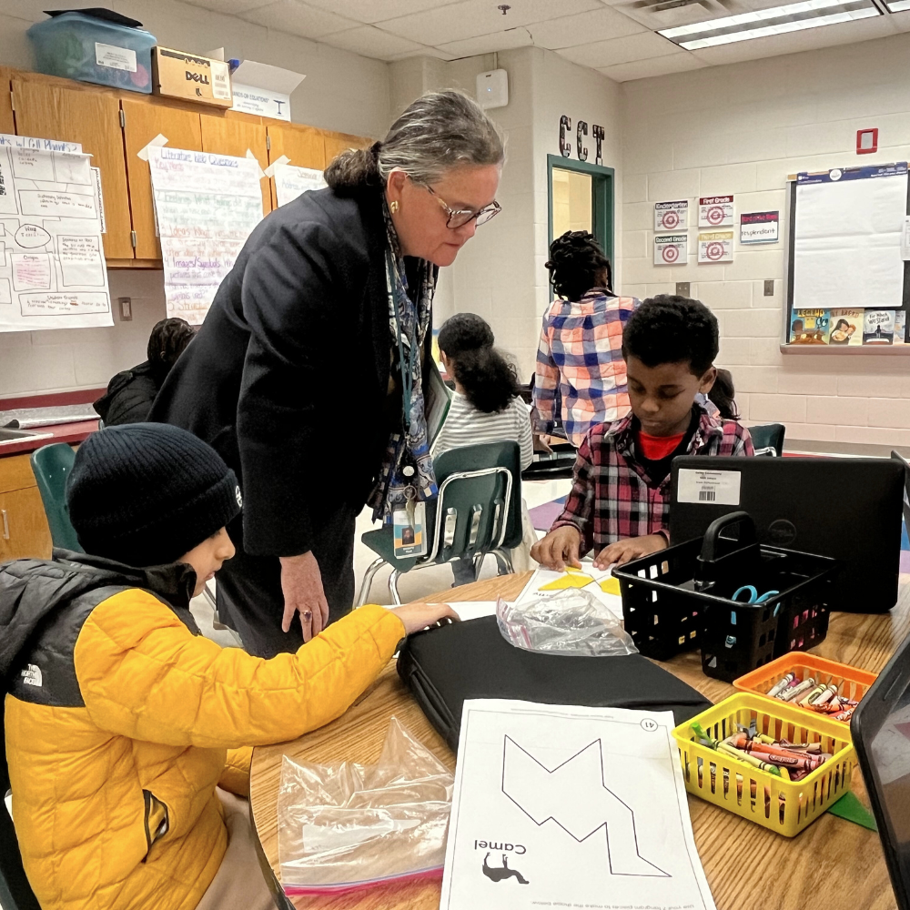 Dr. Reid works with a third grade Halley ES student on a tangram puzzle
